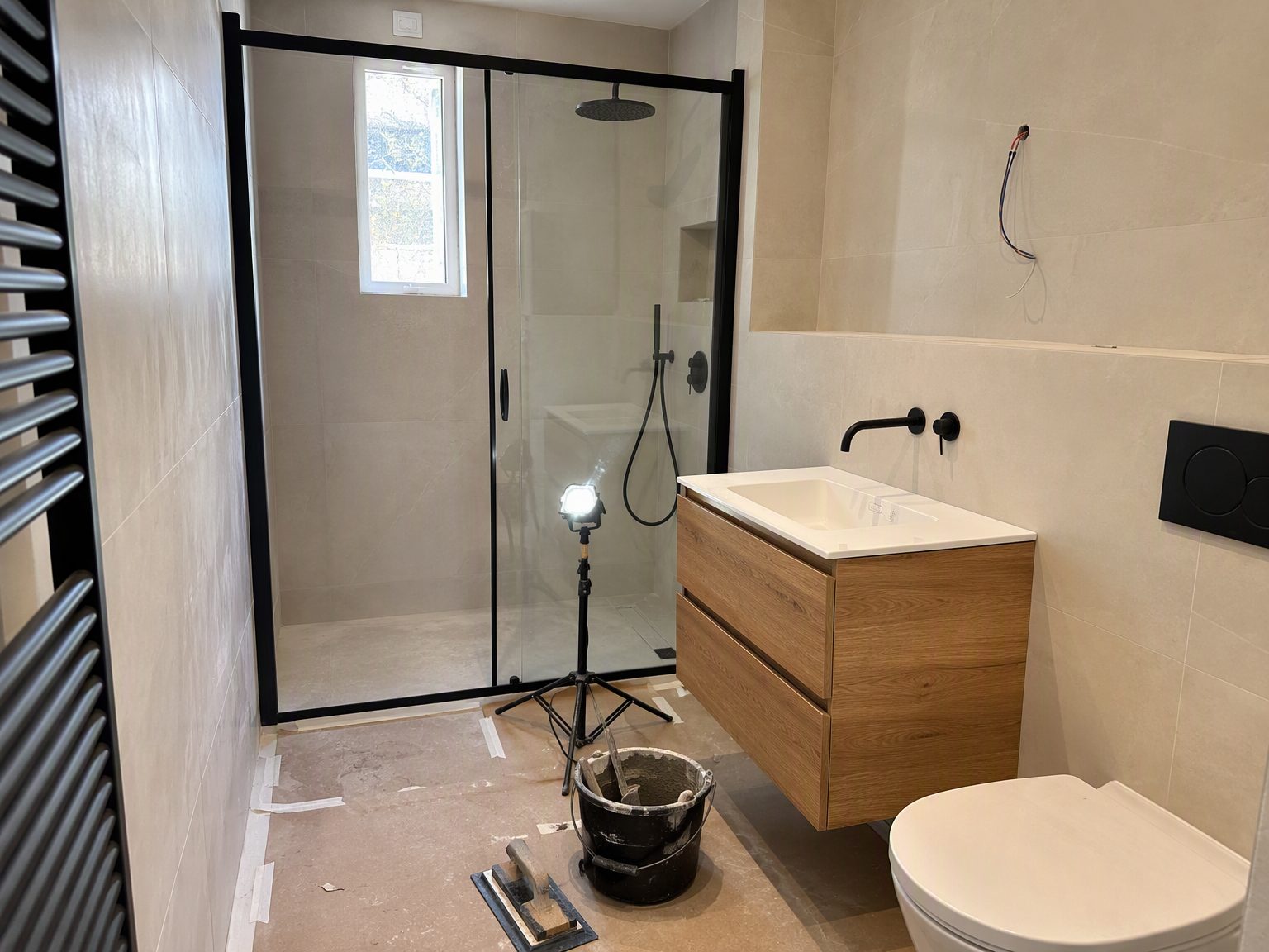 Badkamer in renovatie met inloopdouche en eiken meubel