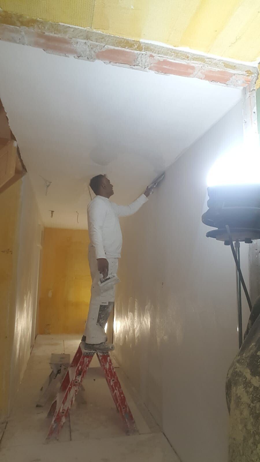 Stukadoor van ABC Klusbedrijf brengt strak stucwerk aan op een plafond